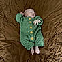Draven is registered to the contest to win money with this photo: baby, sleeping, infant, knitted_outfit, green_clothing, yellow_buttons, quilt, brown_background, soft_texture, peaceful, person, newborn, cute, cozy, resting, portrait, small_feet, hand, sleep, indoors