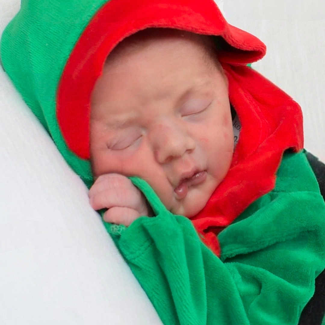 Dallas is registered to the contest to win money with this photo: baby, blanket, child, closeup, cozy, cute, face, green_clothing, hand, hood, indoors, infant, newborn, peaceful, portrait, red_clothing, resting, sleeping, soft_texture, wrapped