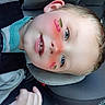 child, face_filter, car_seat, car_interior, blue_eyes, smiling, hand, blond_hair, seatbelt, young_child, cheeks, casual_clothing, partial_face, digital_sticker, playful, closeup, portrait, car_trip, happy, interior