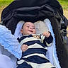 Ilario a rejoint le concours — aidez-le/la à gagner de superbes lots ! baby, blanket, child, clothing, comfort, daytime, greenery, happy, infant, nature, outdoor, park, person, relaxing, smiling, soft_texture, striped_outfit, stroller, sunlight, tree