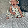 baby, child, smiling, dress, hat, bed, pillow, indoors, happy, person, portrait, cute, sitting, fabric, floral_pattern, headwear, skin, infant, blue_eyes, home