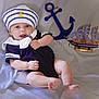 Aaron is registered to the contest to win money with this photo: baby, infant, sailor_hat, navy_outfit, nautical_theme, anchor, toy_ship, smiling, cute, portrait, soft_fabric, indoors, child, happy, skin, arms, legs, headwear, clothing, pose