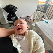 Elina a rejoint le concours — aidez-le/la à gagner de superbes lots ! baby, infant, smile, laughing, cardigan, knitwear, held, lap, person, plastic_chair, table, lighter, balcony, railing, shopping_bag, plastic_bag, floor, indoor_outdoor_space, portrait, candid