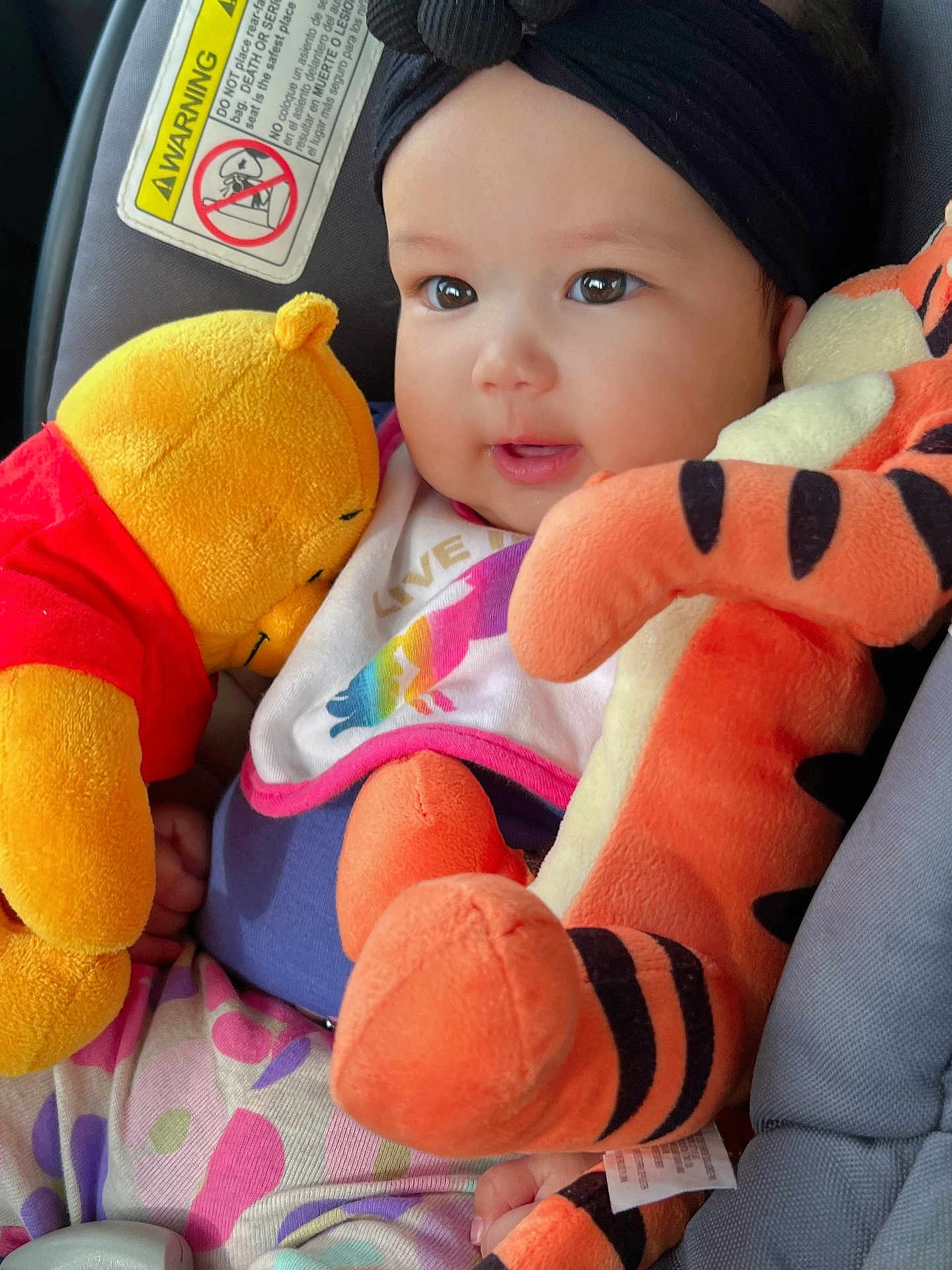 Rhianna is registered to the contest to win money with this photo: baby, child, plush_toy, winnie_the_pooh, tigger, car_seat, headwrap, infant, cute, smiling, colorful_clothing, soft_toys, indoors, closeup, happy, person, toddler, seatbelt, car, portrait