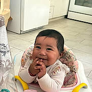 Kamila is registered to the contest to win money with this photo: baby, infant, child, smiling, happy, sitting, walker, baby_walker, hands, fingers, white_sweater, bracelet, pink, colorful, kitchen, indoor, tile_floor, appliances, portrait, playful