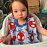 baby_supplies, bib, box, child, clothing, expression, face, food, hair, hand, high_chair, home, indoor, mouth, person, seat, skin, spiderman, toddler, young_child