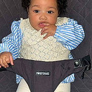 Amaya a rejoint le concours — aidez-le/la à gagner de superbes lots ! baby, child, curly_hair, blue_bow, knitted_vest, striped_shirt, white_pants, baby_seat, comfort, indoor, portrait, cute, sitting, hand_in_mouth, face, eyes, infant, clothing, person, adorable