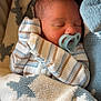 newborn, baby, sleeping, pacifier, blanket, star_pattern, striped_clothing, cozy, infant, cute, soft, wrapped, child, bed, indoors, peaceful, portrait, closeup, resting, warm