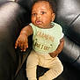 baby, infant, child, bib, clothing, couch, leather, sitting, reaching, hand, face, expression, cute, indoor, person, sock, pants, soft_lighting, curly_hair, portrait