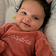 Nalia participe au concours pour gagner de l'argent avec cette photo : baby, infant, smile, face, curly_hair, pink_clothing, soft_texture, lying_down, plush_toy, bed, cozy, cute, child, portrait, indoors, warm_lighting, closeup, expression, human, sleep_area