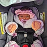 baby, infant, car_seat, pink_bow, pacifier, winter_clothing, fluffy_outfit, mittens, blanket, harness, seat_belt, vehicle_interior, portrait, sitting, baby_face, dark_hair, awake, front_view, safety_seat, cozy