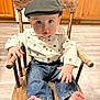 baby, child, hat, shirt, jeans, barefoot, wooden_chair, floor, kitchen, cabinet, curious, indoor, furniture, person, young_child, seated, cute, clothing, face, expression
