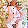 Reigna is registered to the contest to win money with this photo: baby, infant, pacifier, pacifier_clip, knit_hat, pink_outfit, ribbed_knit, buttons, floral_blanket, bed, lying_down, looking_up, hand, feet, newborn, cute, indoor, soft_texture, teether, portrait