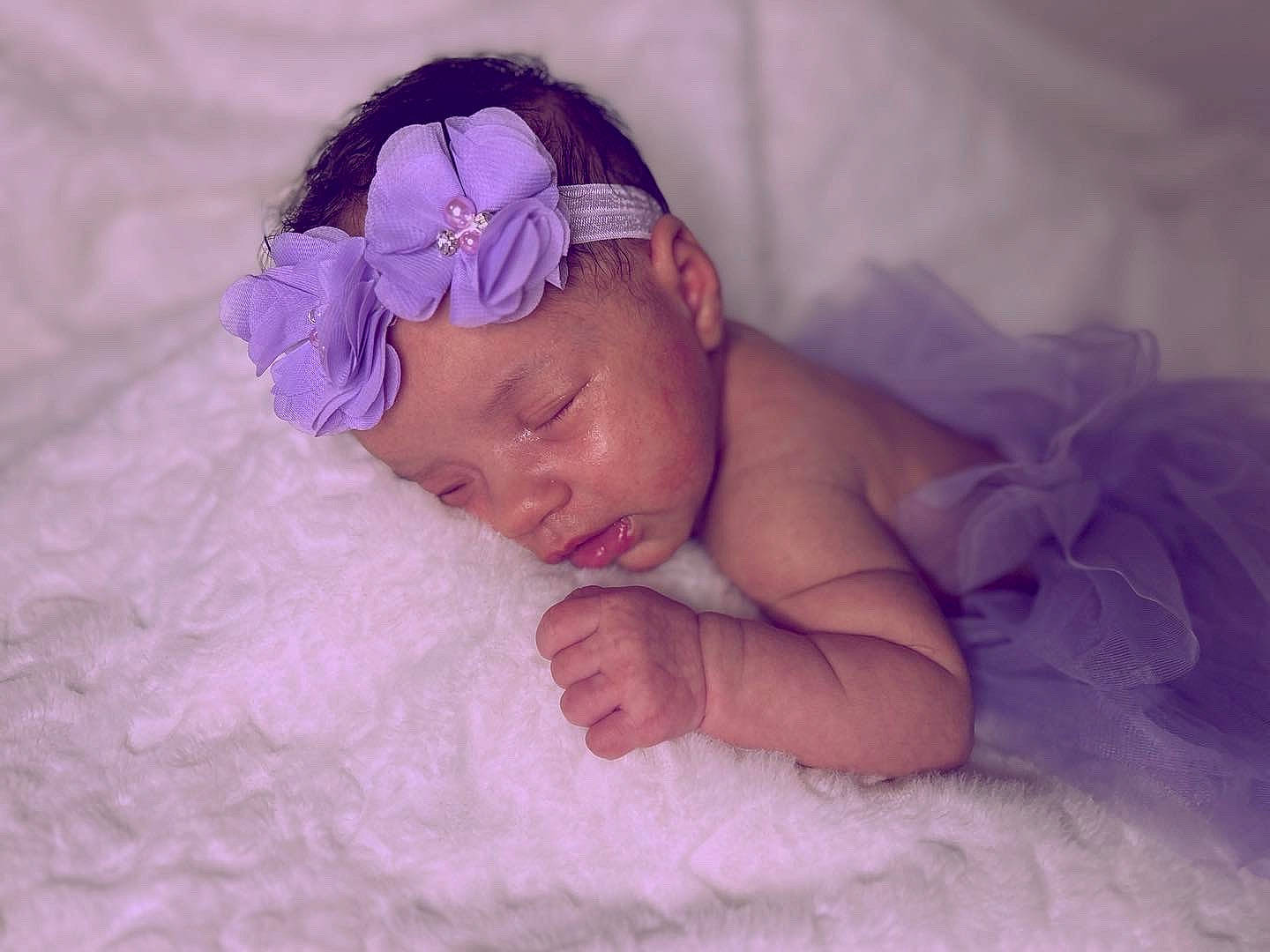 Leilani joined the competition — help win amazing prizes! baby, baby_toddler_clothing, bedding, bedtime, child, comfort, face, fashion_accessory, happy, headgear, headpiece, headwear, linens, magenta, person, petal, pink, purple, skin, smile