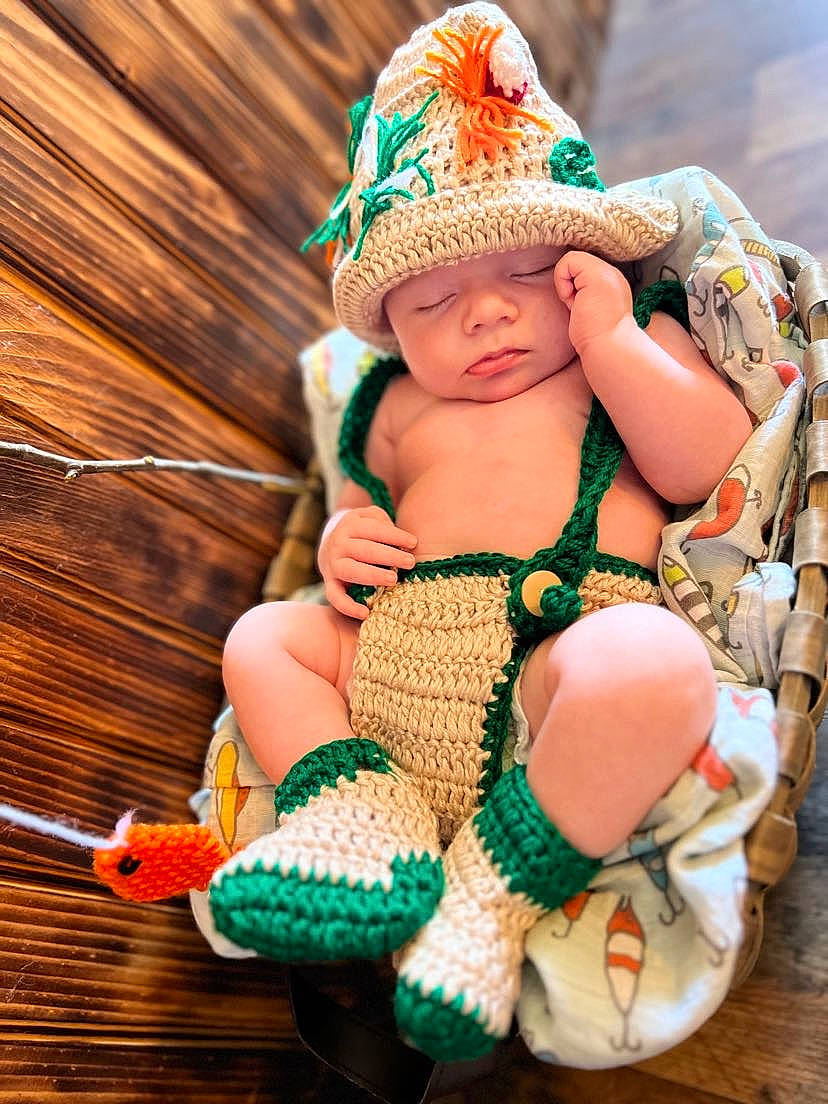 Lance is registered to the contest to win money with this photo: arm, baby, baby_toddler_clothing, cap, child, doll, fashion_accessory, green, happy, hat, headgear, headwear, jewellery, knit_cap, pattern, person, skin, thigh, toddler, toy