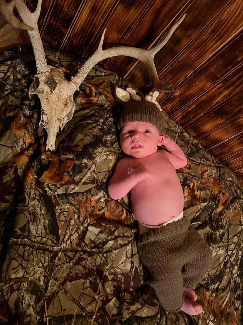 Lance is registered to the contest to win money with this photo: baby, child, deer, fawn, flash_photography, fun, fur, grass, headwear, horn, human_body, organism, people_in_nature, person, plant, reindeer, rock, soil, toddler, trunk