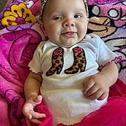 Gracelyn joined the competition — help win amazing prizes! baby, infant, headband, leopard_print, shirt, pink, blanket, smile, tongue, hand, tutu, clothing, cute, face, person, portrait, lying_down, fabric, colorful, indoor