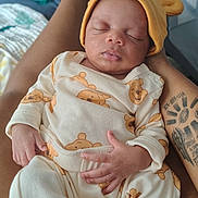 Willow joined the competition — help win amazing prizes! baby, sleeping, infant, bear_outfit, yellow_hat, tattoo, arm, hand, cozy, soft_lighting, indoor, person, child, cute, peaceful, portrait, fabric, clothing, resting, newborn
