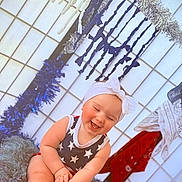 Byrdie is registered to the contest to win money with this photo: baby, bow, child, cute, decorations, festive, fluffy_cushion, happy, headband, holiday, indoor, laughing, onesie, person, portrait, sitting, smiling, star_pattern, streamers, tinsel