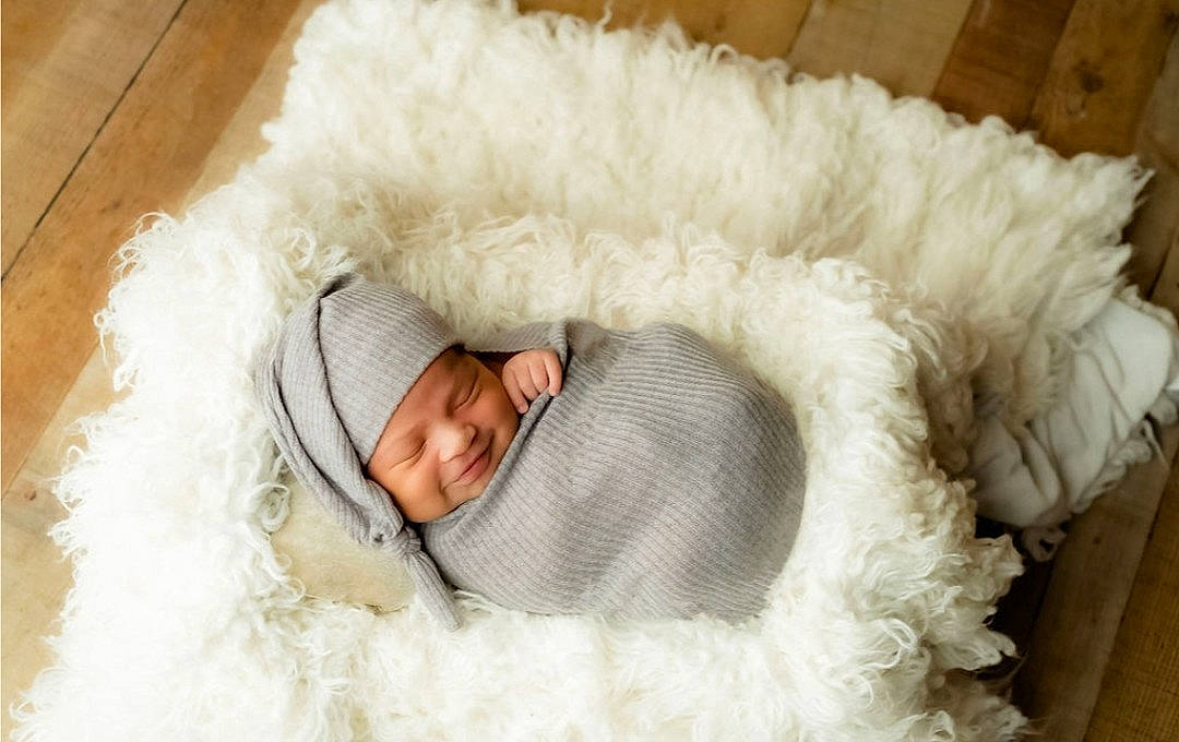 Juan is registered to the contest to win money with this photo: animal_product, baby, baby_sleeping, baby_toddler_clothing, bedtime, blanket, comfort, fur, fur_clothing, hardwood, headwear, joy, linens, nap, natural_material, person, portrait_photography, sleep, textile, wood_stain