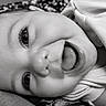 Adaline joined the competition — help win amazing prizes! baby, child, infant, portrait, close_up, black_and_white, smiling, laughing, open_mouth, eyes, face, lying_down, indoor, blanket, clothing, cozy, happy, adorable, photography, head