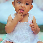 Olivia is registered to the contest to win money with this photo: baby, bodypart, clothing, dress, eating, face, finger, food, frown, hand, happy, head, mouth, newborn, person, photography, portrait, sitting, smile, toe