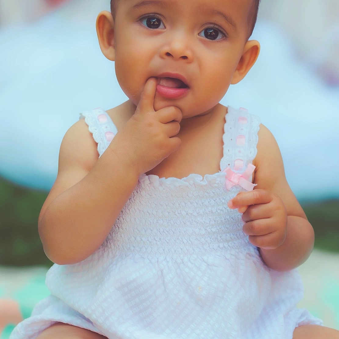 Olivia is registered to the contest to win money with this photo: baby, bodypart, clothing, dress, eating, face, finger, food, frown, hand, happy, head, mouth, newborn, person, photography, portrait, sitting, smile, toe