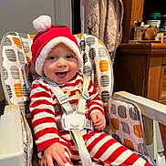 Ayden participe au concours pour gagner de l'argent avec cette photo : baby, child, smiling, high_chair, santa_hat, holiday, red_stripes, white_stripes, pajamas, indoors, happy, cute, infant, seatbelt, face, person, wooden_furniture, cabinet, toy, colorful