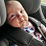 baby, car_seat, child, infant, seatbelt, clothing, onesie, heart_pattern, blue, pink, straps, face, person, car_interior, window, safety, cute, young_child, portrait, closeup
