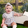 Ariella joined the competition — help win amazing prizes! baby, child, smiling, sitting, headband, floral, blue_eyes, white_clothing, toy_car, wooden_toy, green_grass, background_painting, cute, portrait, happy, indoor, playful, infant, knees, female