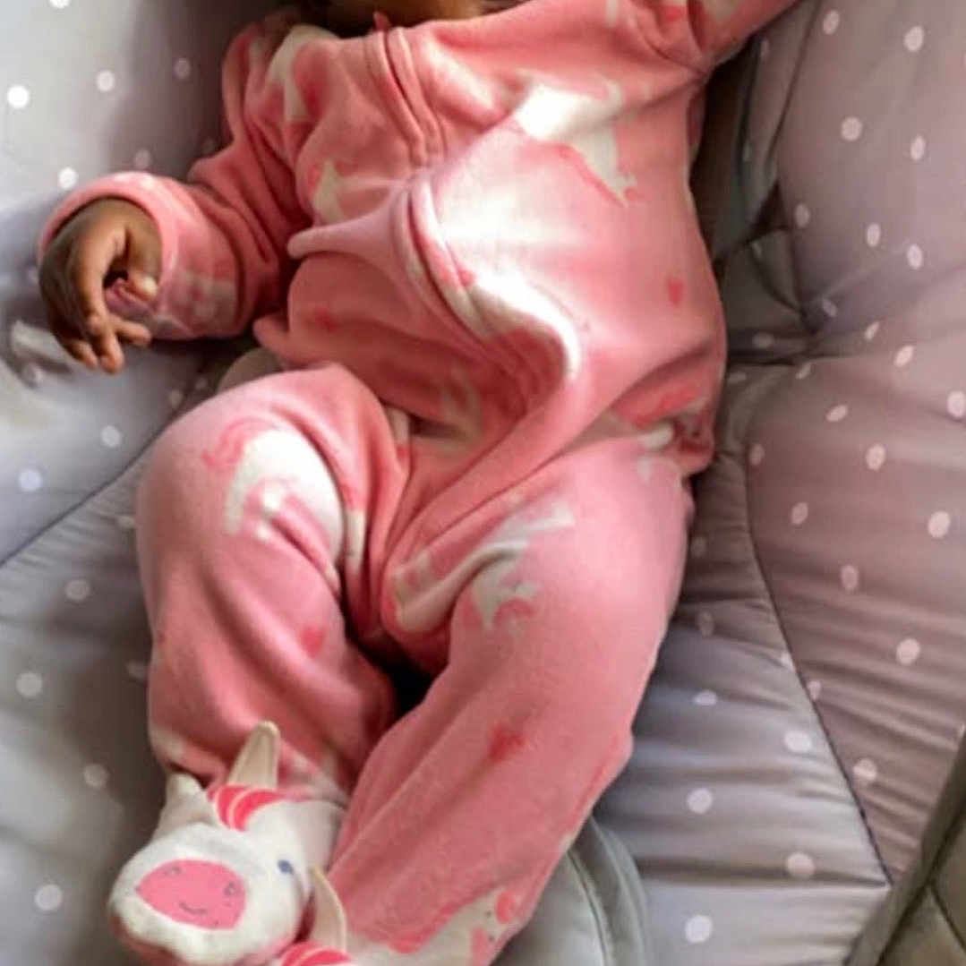 Royale joined the competition — help win amazing prizes! baby, baby_seat, child, comfort, cozy, cushion, cute, footwear, indoor, infant, person, pink_onesie, polka_dot, portrait, relaxed, sleepwear, smiling, soft_toys, unicorn_slippers, young_child