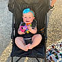 Lexley joined the competition — help win amazing prizes! baby, stroller, toy, headband, blue_bow, smiling, outdoor, gravel, blanket, colorful, child, sunlight, footwear, person, summer, happy, infant, playful, seat, casual
