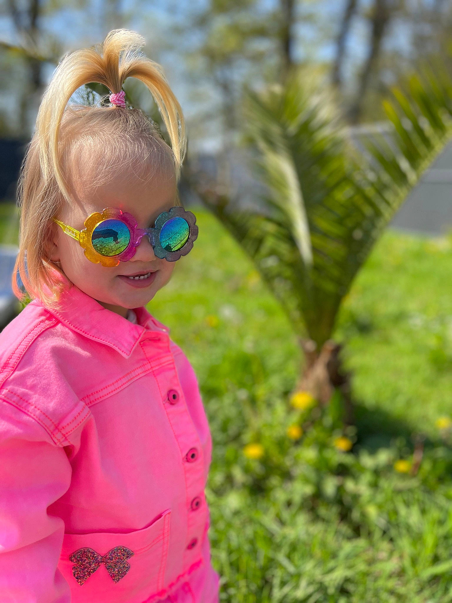 Camille participe au concours pour gagner de l'argent avec cette photo : baby_toddler_clothing, blond, electric_blue, eyewear, face, glasses, goggles, grass, happy, leaf, magenta, people_in_nature, person, pink, plant, sleeve, smile, sunglasses, toddler, tree