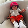 Jax is registered to the contest to win money with this photo: baby, child, smiling, red_cap, gray_tshirt, red_shorts, white_socks, white_sneakers, sitting, armchair, indoors, cute, happy, waving_hand, person, portrait, comfortable, casual_clothing, hair, face