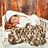 Jaxon joined the competition — help win amazing prizes! newborn, baby, sleeping, knitted_outfit, white_hat, blanket, wooden_bed, brown_pillow, chunky_knit, wooden_floor, wooden_wall, cozy, infant, portrait, indoors, resting, cute, small_bed, soft, warm_colors