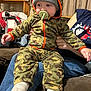 baby, bodypart, cap, clothing, coat, couch, face, footwear, furniture, hat, head, hood, hosiery, jacket, pants, person, photography, portrait, shoe, sock