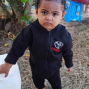 Eleonore participe au concours pour gagner de l'argent avec cette photo : toddler, child, outdoor, tree, grass, plastic_stool, person, black_hoodie, toyota_logo, container, boots, curly_hair, serious_face, nature, leaves, dry_grass, casual_clothing, daylight, standing, holding