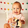 Amelia joined the competition — help win amazing prizes! baby, child, smiling, pink_clothing, plush_toy, penguin_toy, dimples, birthday, number_one, decorations, colorful_pom_poms, white_brick_wall, sitting, happy, cute, portrait, indoors, bracelet, toy, celebration