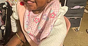 Kaylani is registered to the contest to win money with this photo: arm, baby, bib, child, clothing, cute, floor, footwear, furniture, hair_bows, happy, holding, indoor, infant, person, pink, smiling, tattoo, toy, young