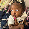 Kaylani joined the competition — help win amazing prizes! baby, child, curly_hair, hair_clips, hand, pink_nail_polish, white_shirt, face, looking_away, bed, blanket, winnie_the_pooh, baby_seat, earrings, indoor, person, cute, expression, holding, toddler