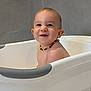 baby, bathroom, bathtub, child, clean, closeup, cute, face, happy, head, indoors, joyful, necklace, person, sitting, skin, smile, water_droplets, wet, young_child