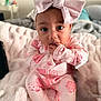 baby, child, pink_bow, headband, onesie, ladybug_pattern, blanket, soft_texture, indoor, cute, portrait, finger_in_mouth, sitting, infant, cozy, clothing, young_child, person, face, curious