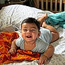 baby, smiling, bed, blanket, crib, room, child, infant, happy, indoors, furniture, orange_cloth, person, sleepwear, wooden_crib, pillow, head, face, hand, foot