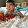 Atharv is registered to the contest to win money with this photo: baby, child, smiling, bed, blanket, orange_cloth, indoor, face, person, happy, cute, infant, sleepwear, home, portrait, lying_down, head, hands, light, cozy