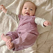 Camille participe au concours pour gagner de l'argent avec cette photo : baby, infant, smiling, romper, blanket, cute, happy, clothing, foot, hand, face, lying_down, soft_texture, child, playful, indoors, person, apparel, head, skin