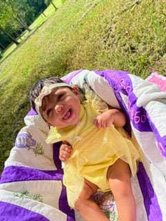 Kensleigh joined the competition — help win amazing prizes! botany, child, costume, dress, event, fun, grass, happy, headwear, lap, leisure, magenta, people_in_nature, person, pink, plant, play, purple, recreation, sitting