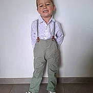 Mayron participe au concours pour gagner de l'argent avec cette photo : child, boy, smiling, standing, white_shirt, suspenders, green_pants, white_shoes, indoor, wall, floor, tile, hair, happy, casual, portrait, fashion, feet, full_body, person
