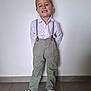 child, boy, smiling, standing, white_shirt, suspenders, green_pants, white_shoes, indoor, wall, floor, tile, hair, happy, casual, portrait, fashion, feet, full_body, person