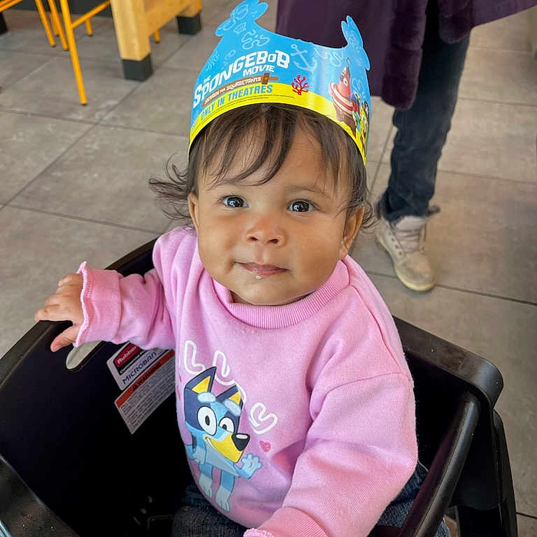 Jacquelyn joined the competition — help win amazing prizes! bluey, cartoon_character, casual_shoes, child, clothing, curly_hair, cute, indoor, paper_crown, person, pink_sweatshirt, playful, portrait, seated, smiling, spongebob, stroller, tile_floor, toddler, young_child