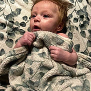 Ruby joined the competition — help win amazing prizes! baby, blanket, infant, face, hands, hair, soft_texture, pattern, curious, child, cute, skin, young, portrait, indoors, expression, comfort, warmth, lying_down, person
